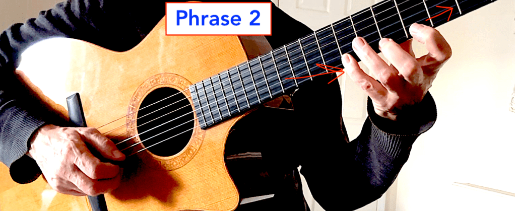 Close-up of a guitarist's hand demonstrating finger positioning on the fretboard with an arrow indicating the movement for phrase 2 for alternate picking guitar technique.